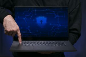 Laptop screen showing digital lock icon with cybersecurity elements like firewall and encryption in a high-tech workspace.